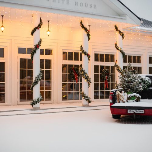 picture front yard of a house a red car is parked and Christmas lights and Christmas decoration with yellow lighting