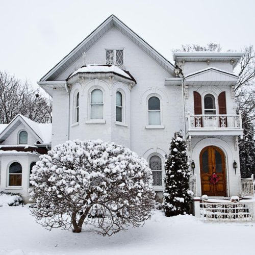 front view of a house surrounded by trees covered under snow