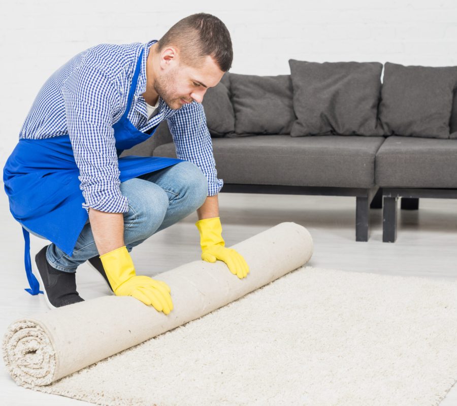 picture of a house cleaning services man rolling a carpet